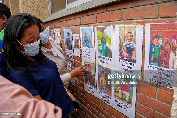 People look at photographs of individuals reported missing following devastating flash floods in Nepal, outside Tribhuvan University Teaching...