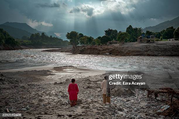 Women view the widened channel of the Trishuli River following flash floods on August 29, 2026 in Devighat, Nepal. A sudden flood swept through the...