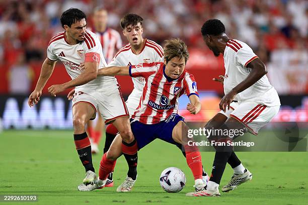 Lee Kang-In of Atletico de Madrid is challenged by Lucien Agoume and Gabriel Suazo of Sevilla during the LaLiga EA Sports 2026/27 match between...