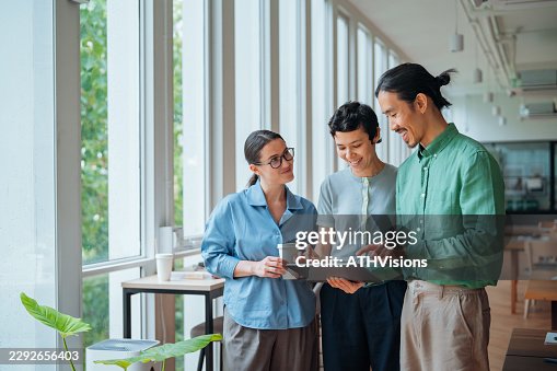 Three Professionals Sharing Ideas in Modern Shared Workspace Three Professionals Sharing Ideas in Modern Shared Workspace