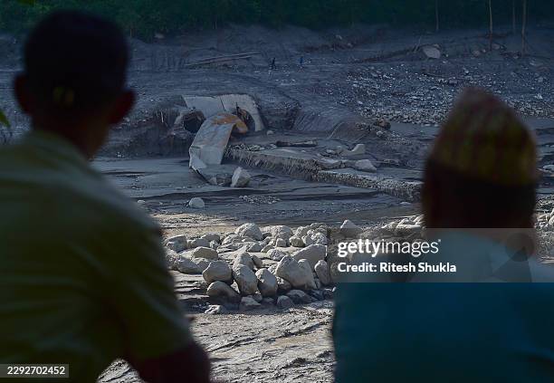 Local residents look at a damaged tunnel of the Trishuli Hydropower Plant on the banks of the swollen Trishuli River following landslides on August...