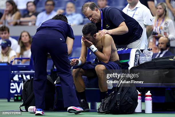 Novak Djokovic of Serbia receives treatment from Clay Sniteman against Mariano Navone of Argentina during their Men's Singles First Round match on...