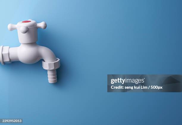 white plastic water tap on a vibrant blue background - stopcock stock pictures, royalty-free photos & images