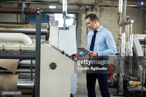 Factory manager working on machine control panel Factory manager working on machine control panel