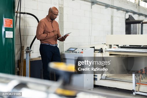 Engineer checking production line equipment at a modern manufacturing factory Engineer checking production line equipment at a modern manufacturing factory