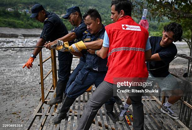 Nepal police personnel pull the rope of makeshift manual zip line across the Trishuli river following flash floods on September 04, 2026 in Nuwakot,...