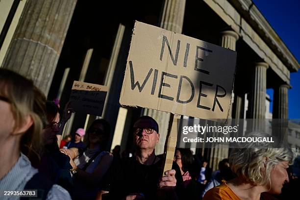 People protest and hold a placard reading "Never again" during a rally called by the organizations Campact and Fridays for Future named "Time to Act:...