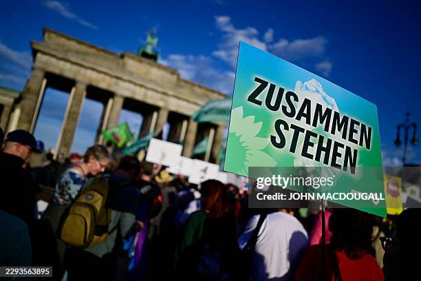 People protest and hold placards reading "Standing together" during a rally called by the organizations Campact and Fridays for Future named "Time to...