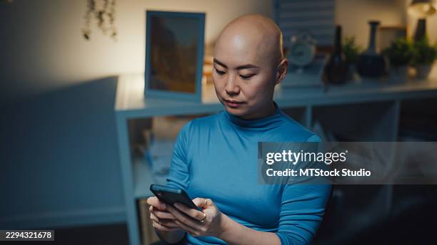 young asian female programmer with cancer patient using smartphone while coding on computer in home at the night. network security, chatbot, software development, artificial intelligence concept. - javascript stock pictures, royalty-free photos & images
