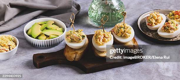 deviled eggs with tomatoes and avocado on toast on a board web banner - deviled eggs stock pictures, royalty-free photos & images