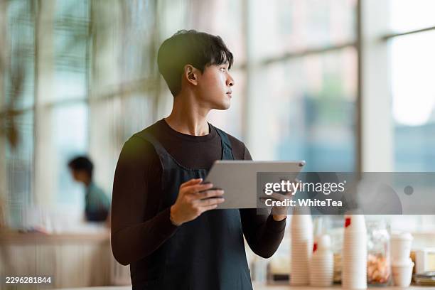 cafe worker using tablet while looking out window - click collect stock pictures, royalty-free photos & images