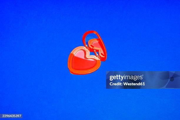 open red heart shaped makeup compact on blue background - mirror different reflection stock illustrations