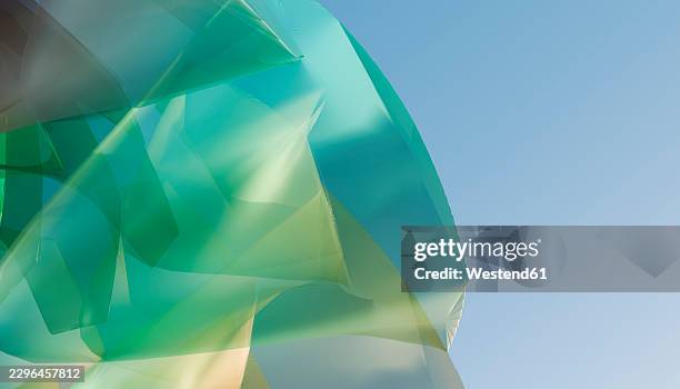 abstract turquoise polygon structure stands against a clear blue sky - light installation stock illustrations