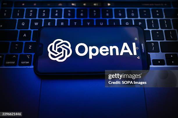 In this photo illustration, an OpenAI logo is seen displayed on a smartphone on the top of a laptop.