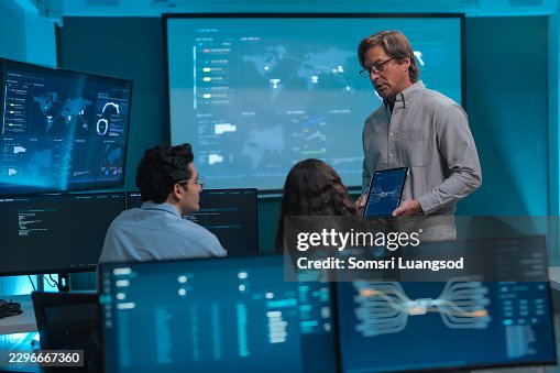 Control room manager using tablet while discussing system monitoring with team Control room manager using tablet while discussing system monitoring with team