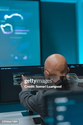 Control room operator pointing at computer screen during network data analysis Control room operator pointing at computer screen during network data analysis