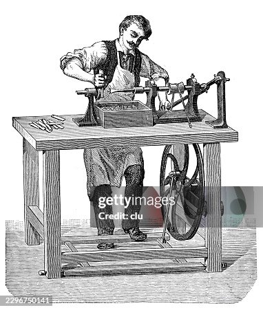 Worker operating a button lathe — craftsman making small buttons on a foot-powered turning machine with treadle wheel and collecting the workpieces in a box Worker operating a button lathe — craftsman making small buttons on a foot-powered turning machine with treadle wheel and collecting the workpieces in a box