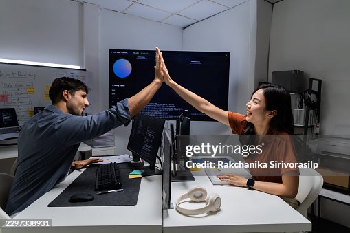 AI engineer and software developer exchange a high five across office desks after training update succeeds, celebrating collaboration, coding progress, and machine learning teamwork, IT support AI engineer and software developer exchange a high five across office desks after training update succeeds, celebrating collaboration, coding progress, and machine learning teamwork, IT support