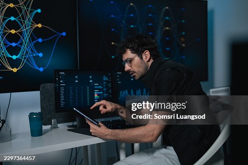 Programmer using tablet while checking network data on screen Programmer using tablet while checking network data on screen