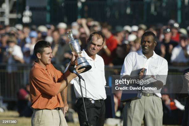 Ben Curtis of the USA receives the Claret Jug as runners-up Thomas Bjorn and Vijay Singh celebrate after the Open Championship at the Royal St....