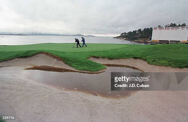 Greenskeepers squeegee the waterlogged 18th green at Pebble Beach Golf Course before the third round of the AT&T Pebble Beach National Pro-Am. Rain...