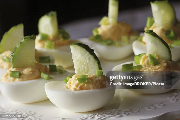 spicy deviled eggs garnished with cucumber and leek on white plate - deviled eggs stock pictures, royalty-free photos & images