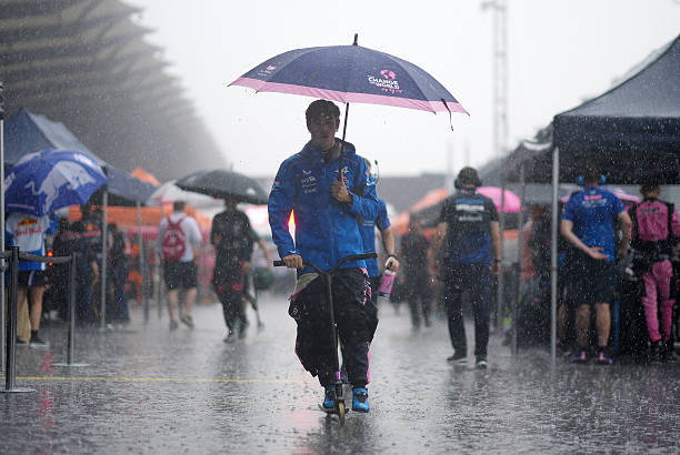 Franco Colapinto of Argentina and Alpine F1 rides his scooter as he shelters from the rain underneath an umbrella on the grid prior to the F1 Grand...
