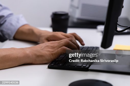 Computer Programmer typing at a computer keyboard, close-up hand and computer equipment at a desk, using computer at a modern office, computer language, software development and technology. Computer Programmer typing at a computer keyboard, close-up hand and computer equipment at a desk, using computer at a modern office, computer language, software development and technology.