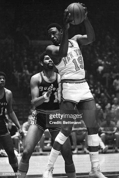 Willis Reed pulls down a rebound against Baltimore in the fourth NBA playoff game as Ray Scott stands behind him.