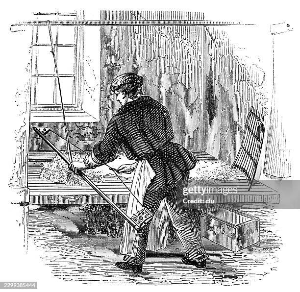 hat maker manually bowing fur fibers — young craftsman wearing a cap, dark jacket and light apron uses a large bow to separate and distribute loose wool or fur fibers on a workbench in a workshop for felt hat production - work bench stock illustrations