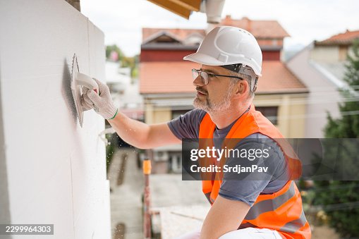 Construction Worker Sanding Polystyrene Facade Insulation Construction Worker Sanding Polystyrene Facade Insulation
