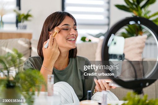 Young Woman Filming A Makeup Tutorial Using Her Phone And A Ring Light At Home Young Woman Filming A Makeup Tutorial Using Her Phone And A Ring Light At Home