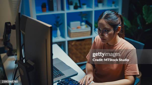 gen z asian female computer programmer types coding on a laptop while working late at night in home office. professional software development, digital transformation, artificial intelligence concept. - application programming interface stock pictures, royalty-free photos & images
