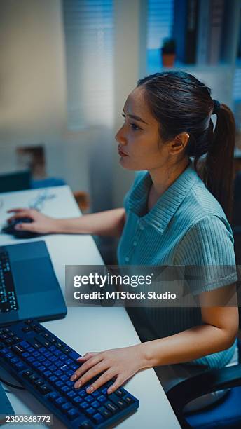 gen z asian female computer programmer types coding on a laptop while working late at night in home office. professional software development, digital transformation, artificial intelligence concept. - application programming interface stock pictures, royalty-free photos & images