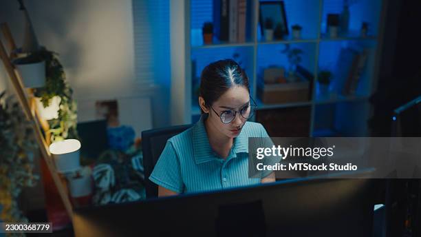 gen z asian female computer programmer types coding on a laptop while working late at night in home office. professional software development, digital transformation, artificial intelligence concept. - application programming interface stock pictures, royalty-free photos & images