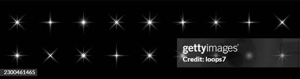 white sparkling starburst light effects set on black background - flashlight isolated stock illustrations
