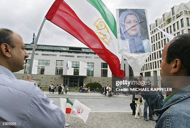 Some twenty Iranian opposition supporters of the People's Mujahedeen organisation display the Iranian flag and a portrait of their organization's...