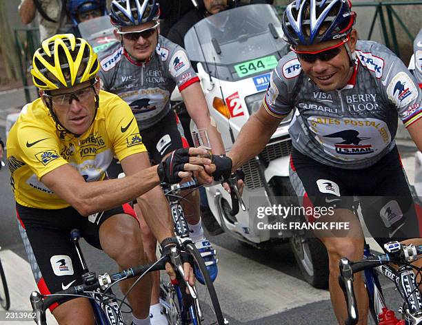 Lance Armstrong gives a glass of champain to his Russian teammate Vjatceslav Ekimov during the 20th and last stage of the 90th Tour de France cycling...