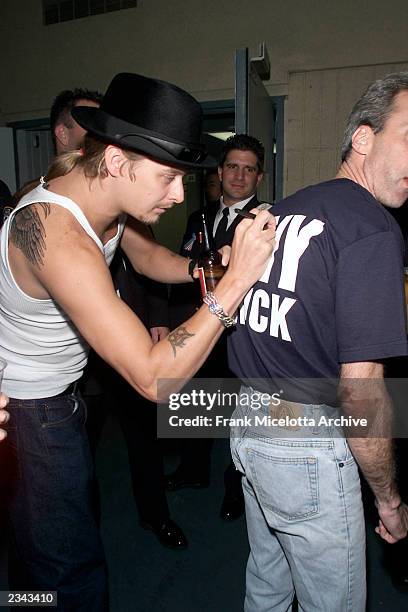 Kid Rock autographs the back of one of New York City's bravest, member of the NYC Fire Department backstage at The Concert for New York City to...