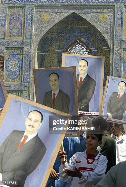 An Iraqi boy holds up pictures of Al-Sharif Ali bin al-Hussein, the son of a cousin of former Iraqi King Ghazi and pretender to the Iraqi throne,...