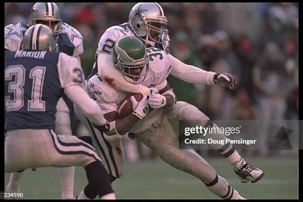 Running back Ricky Watters of the Philadelphia Eagles is tackled from behind by a Dallas Cowboy and blocked in front by safety Brock Marion at...
