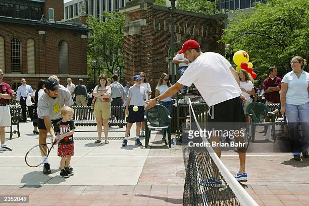 Justin Gimelstob tosses the ball to young Brian Maddox while Robby Ginepri helps as they promote the 2003 RCA Championships by playing a short match...