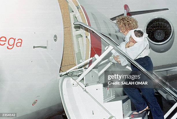 An unidentified British nurse carries the Sudanese boy who emerged as the sole survivor of a plane crash earlier this week into a chartered Swiss...