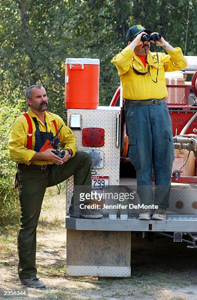 Firefighters Barry Sherman and Dan Ryan of Kootenai County Fire and Rescue watch as a helicopter drops incendiary balls onto trees August 1, 2003 on...