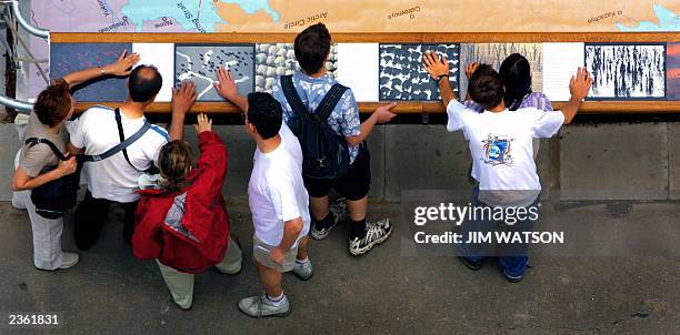 Spectators run their hands across Yann Arthus-Bertrand's exhibit "Earth from the Air Seen By Blind People" which features his photos specially...