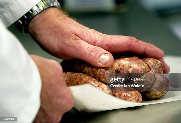 Butcher prepares pork sausages in his shop August 4, 2003 in London. Sales of red meat in Britain are at their highest levels ever as the...