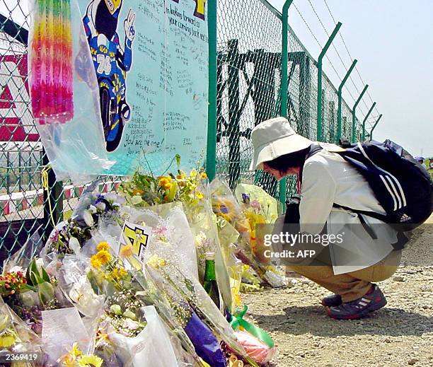 Tomoko Shimizu, a 41-year-old Japanese female office employee offers a bouquet and kneels down before the fence of the Suzuka circuit, where Japanese...