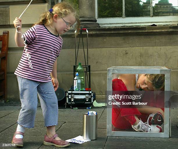 Child looks at a contortionist in a box on the sidewalk at the 57th Edinburgh Festival Fringe 2003 August 4, 2003 in Edinburgh, Scotland. The...