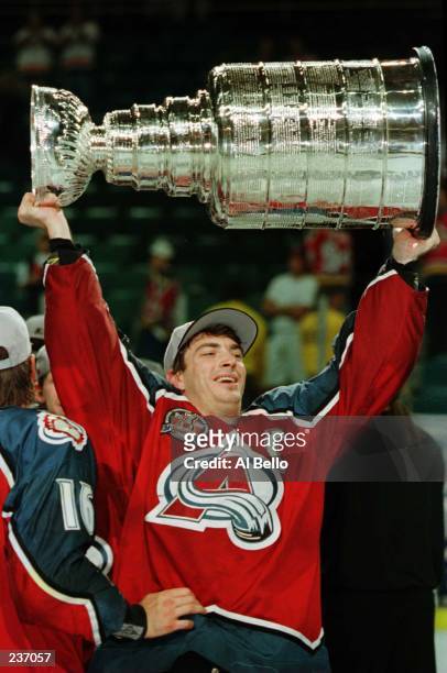 Joe Sakic, captain of the Colorado Avalanche hoists the Stanley Cup trophy after defeating the Florida Panthers, 1-0, in triple overtime of game four...