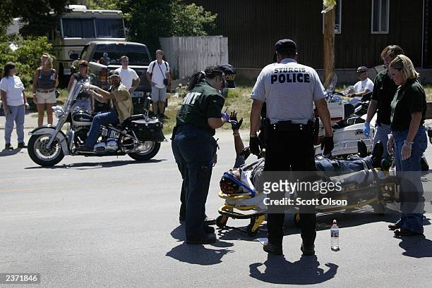 Bikers drive by a motorcyclist that was injured in a collision with a truck at the annual Sturgis Motorcycle Rally August 5, 2003 in Sturgis, South...